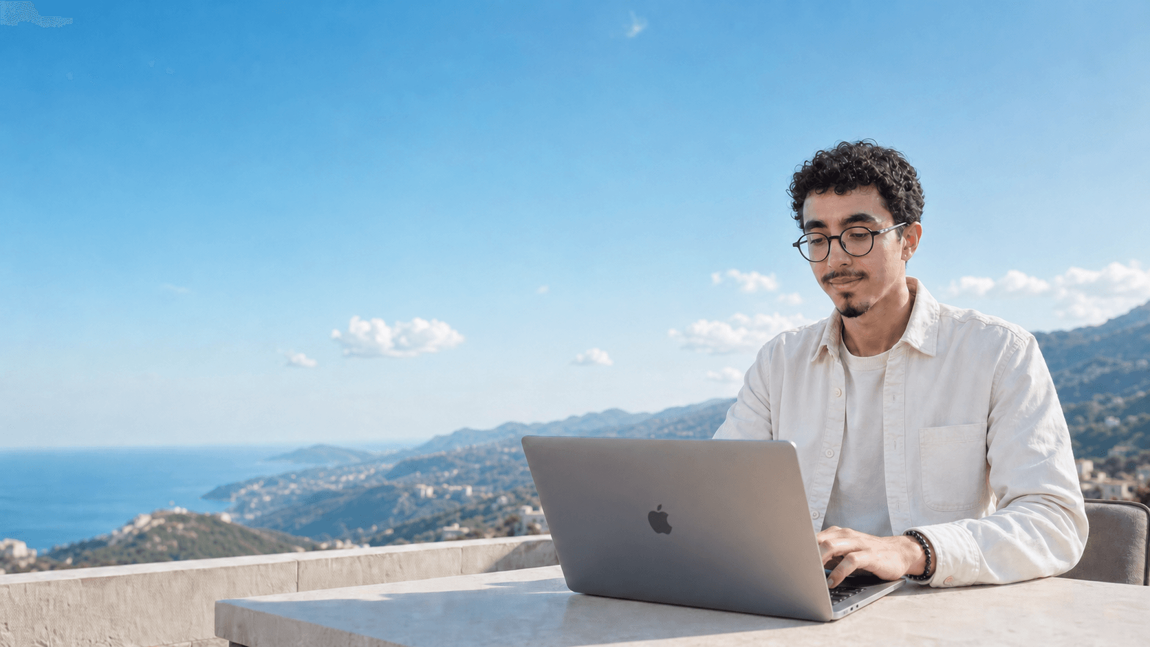 Charbel working on a MacBook above the Mediterranean mountains